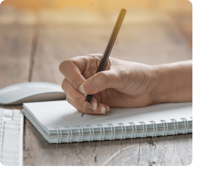 A hand writing on a notebook with a pen.