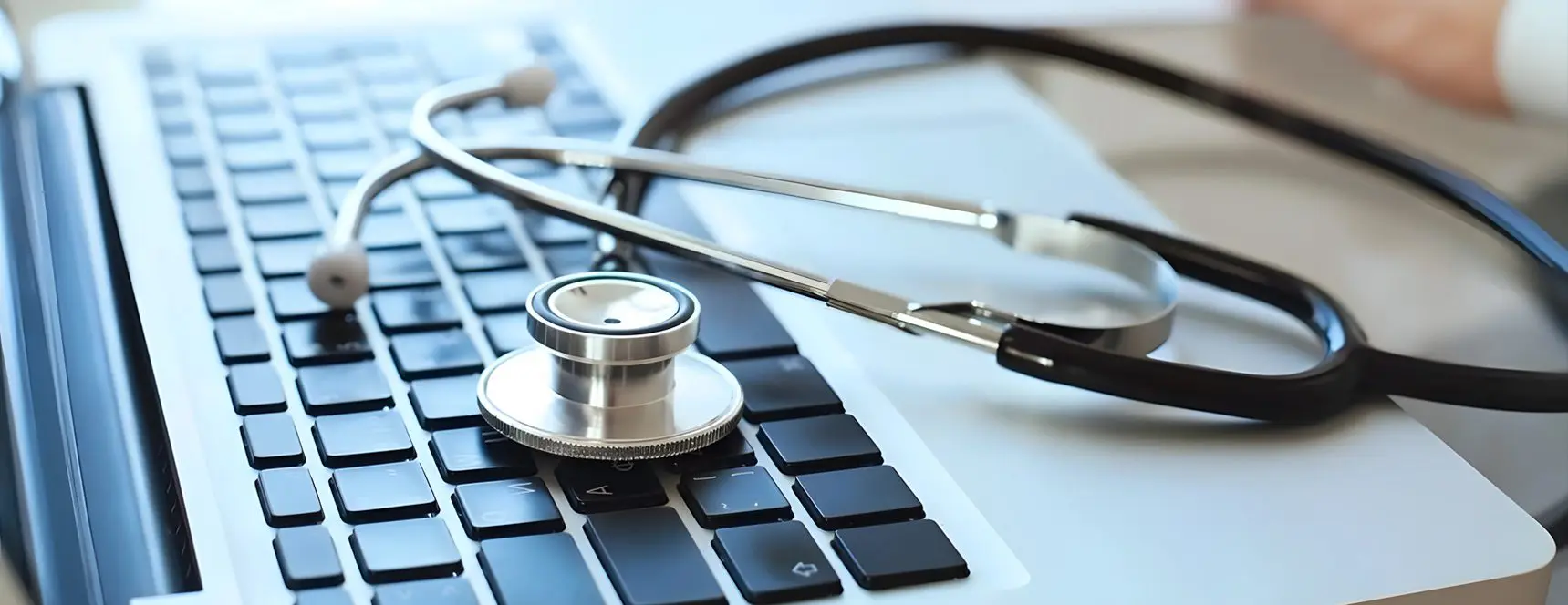 A stethoscope sits on top of a laptop keyboard.